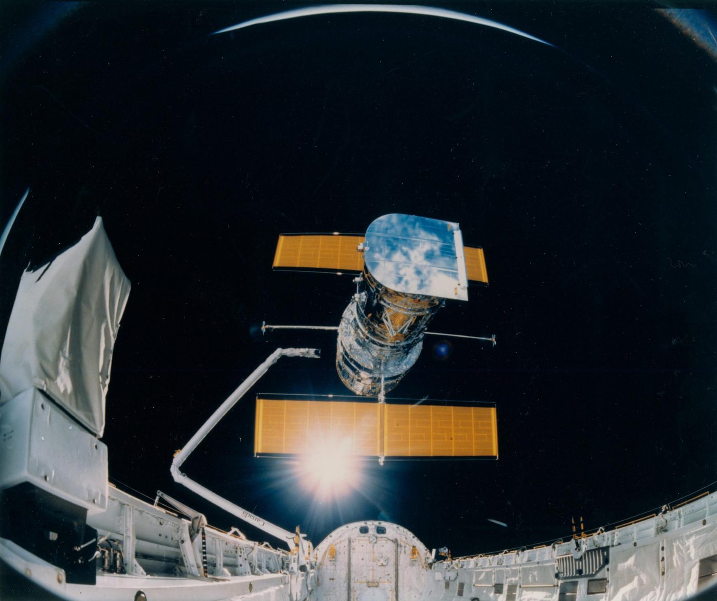O Telescópio Espacial Hubble sendo liberado da baia de carga do ônibus espacial Discovery em 25 de abril de 1990, em foto feita por uma câmera IMAX do ônibus espacial