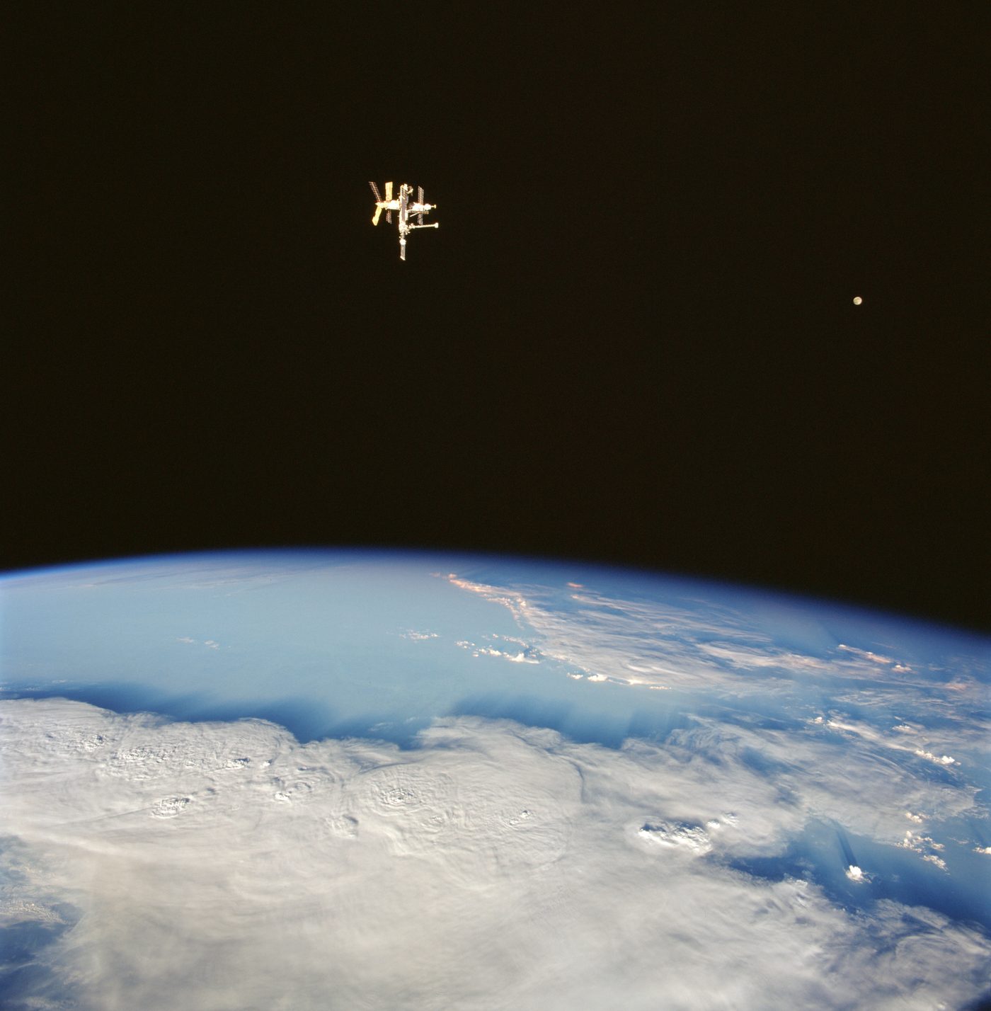 A estação espacial Mir e a Lua na mesma fotografia, feita por tripulantes do ônibus espacial Discovery na missão STS-91, em junho de 1998