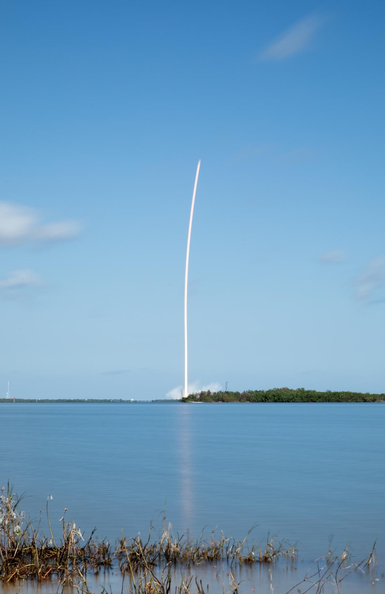 Rastro branco de fumaça no céu azul da Flórida marca a trajetória da Europa Clipper logo após deixar a plataforma de lançamento.
